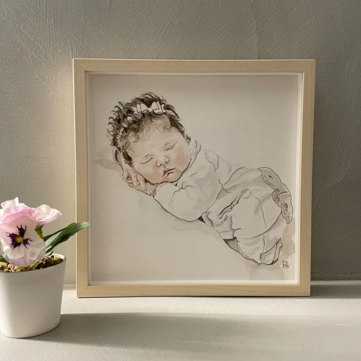 Babyportret in aquarel: een slapende baby met haarbandje, ingelijst in een blank houten lijst.